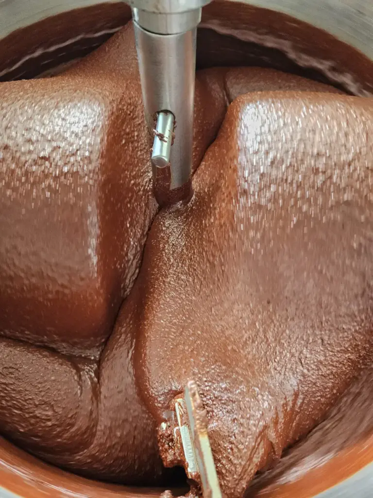 Gęsta, płynna masa czekoladowa podczas wielogodzinnego procesu rozcierania w kamiennym młynie