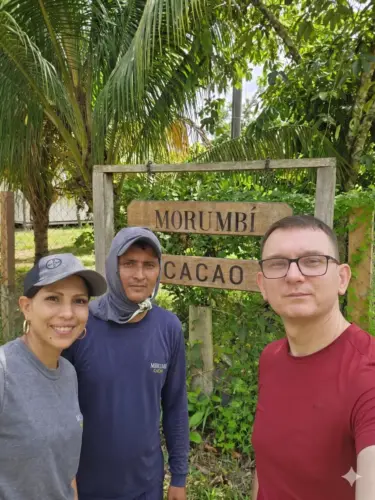 Właściciel manufaktury Beskid Chocolate wraz z lokalnymi plantatorami na tle drewnianego szyldu plantacji Morumbí Cacao w Kolumbii