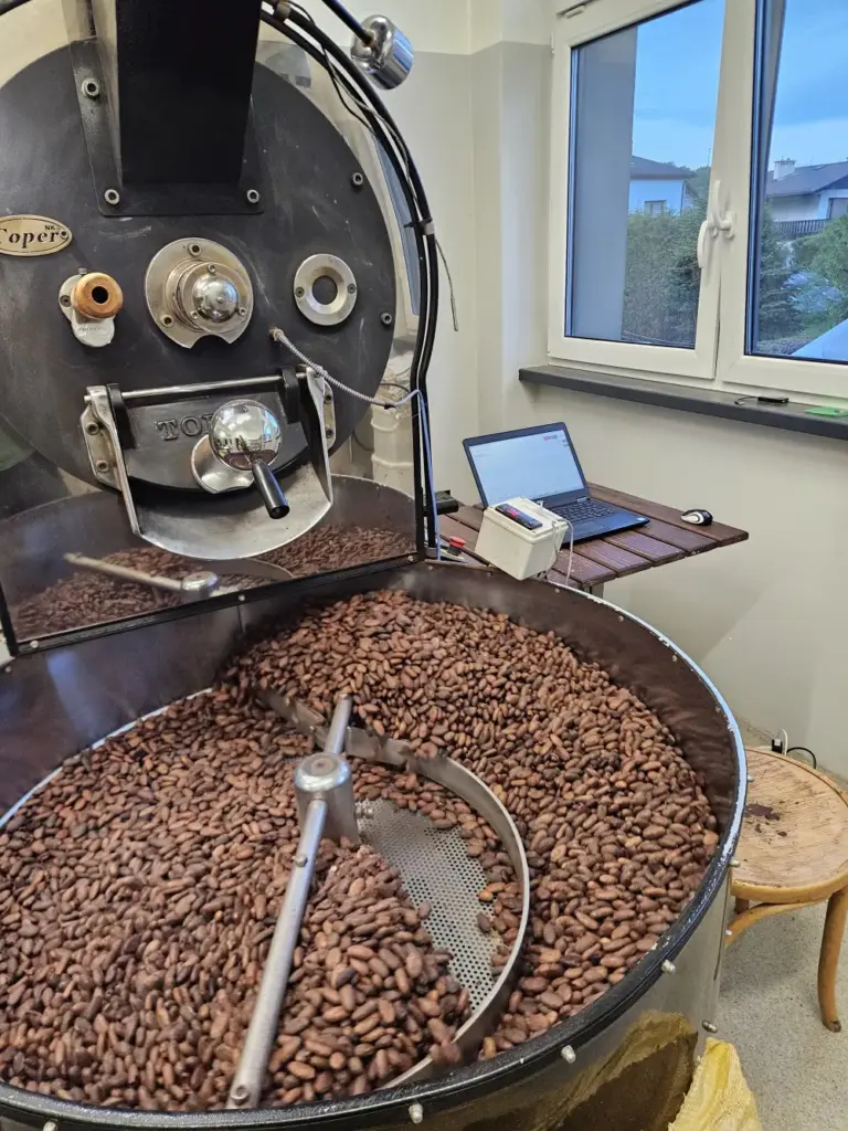Rozgrzane ziarna kakao obracające się w bębnie rzemieślniczego pieca do prażenia w manufakturze Beskid Chocolate
